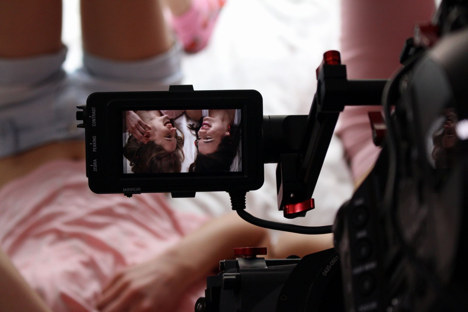 Een camera filmt de hoofden van twee meiden op bed. In de achtergrond zijn de benen van de meiden zichtbaar. Foto is genomen op de set van Koppie.