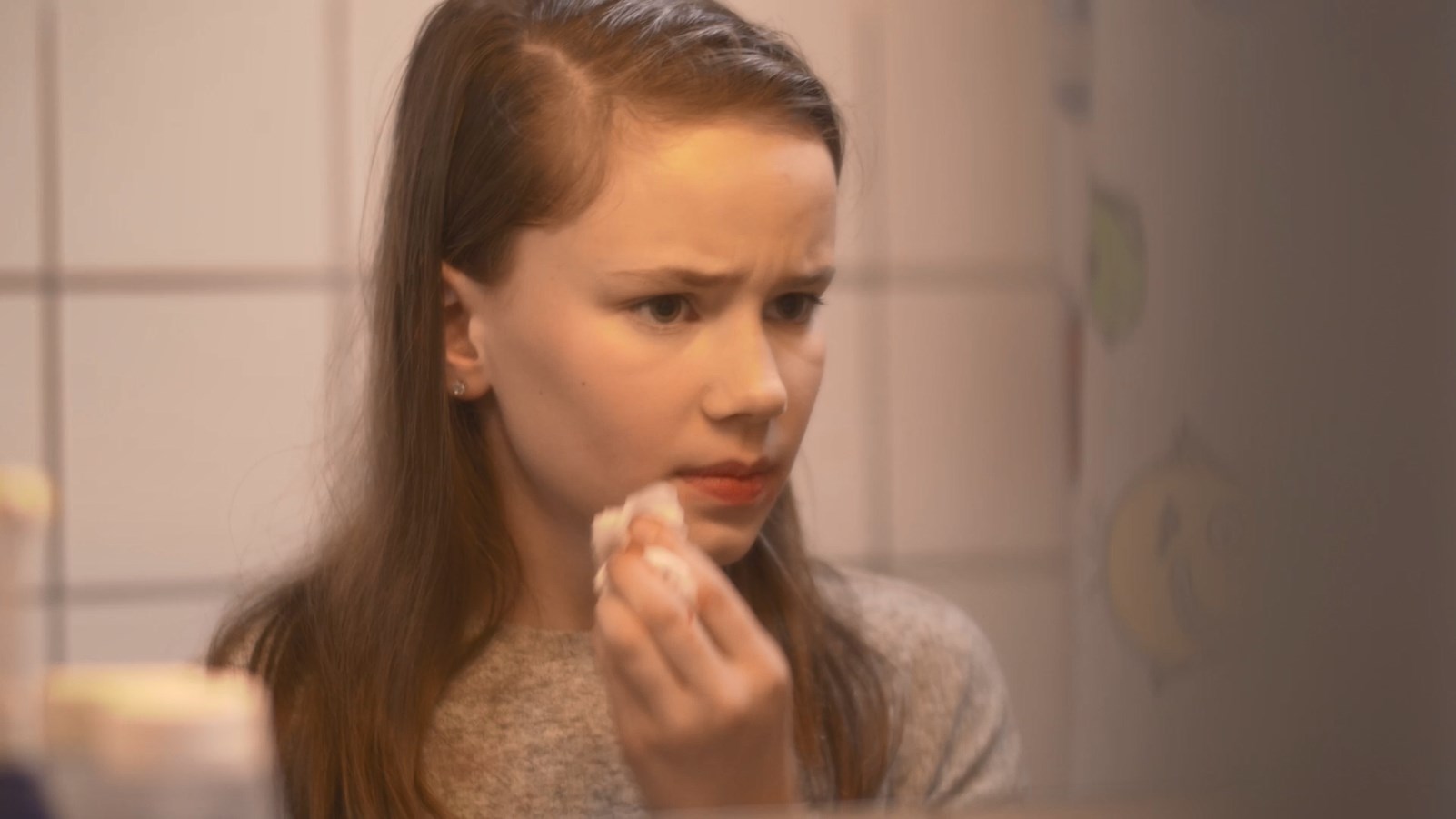 Een meisje haalt make-up van haar gezicht op de badkamer. Het is een still uit de film 'Een dochter van een vader'.